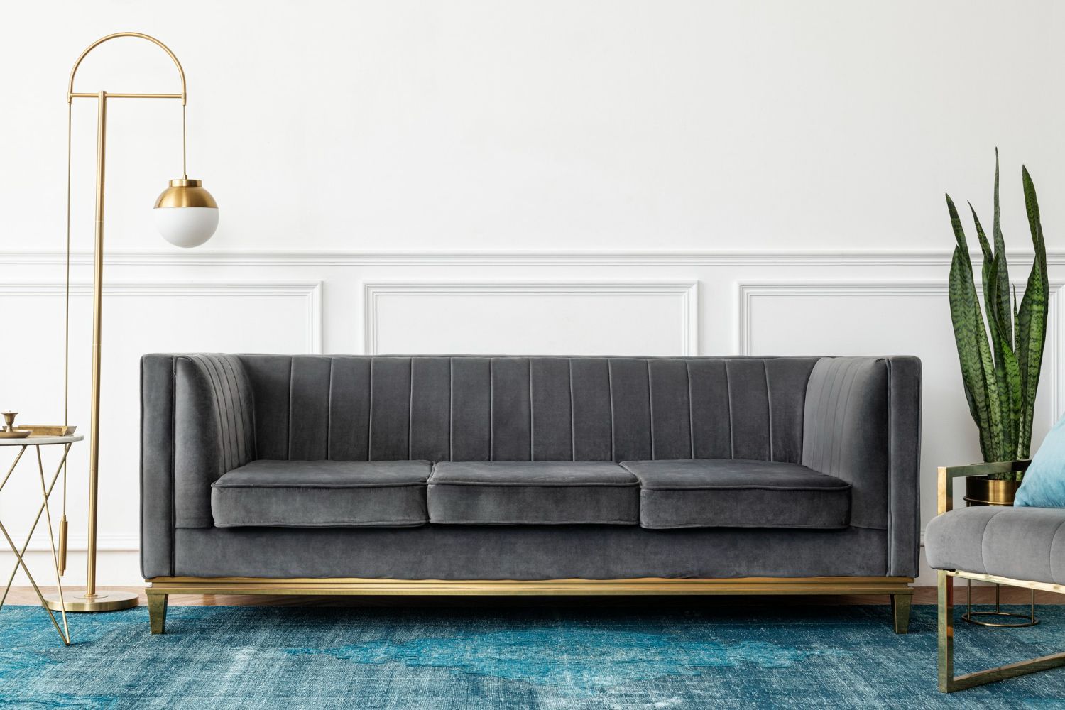A living room with a gray couch and a blue rug.