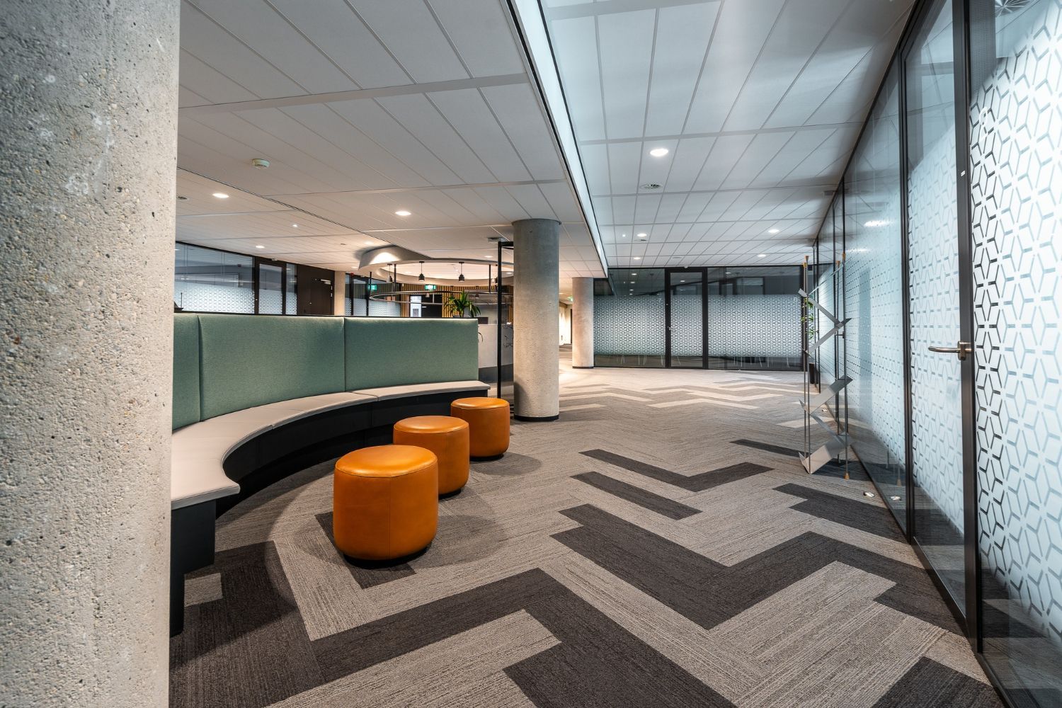 A hallway with a chevron pattern on the floor and a bench.